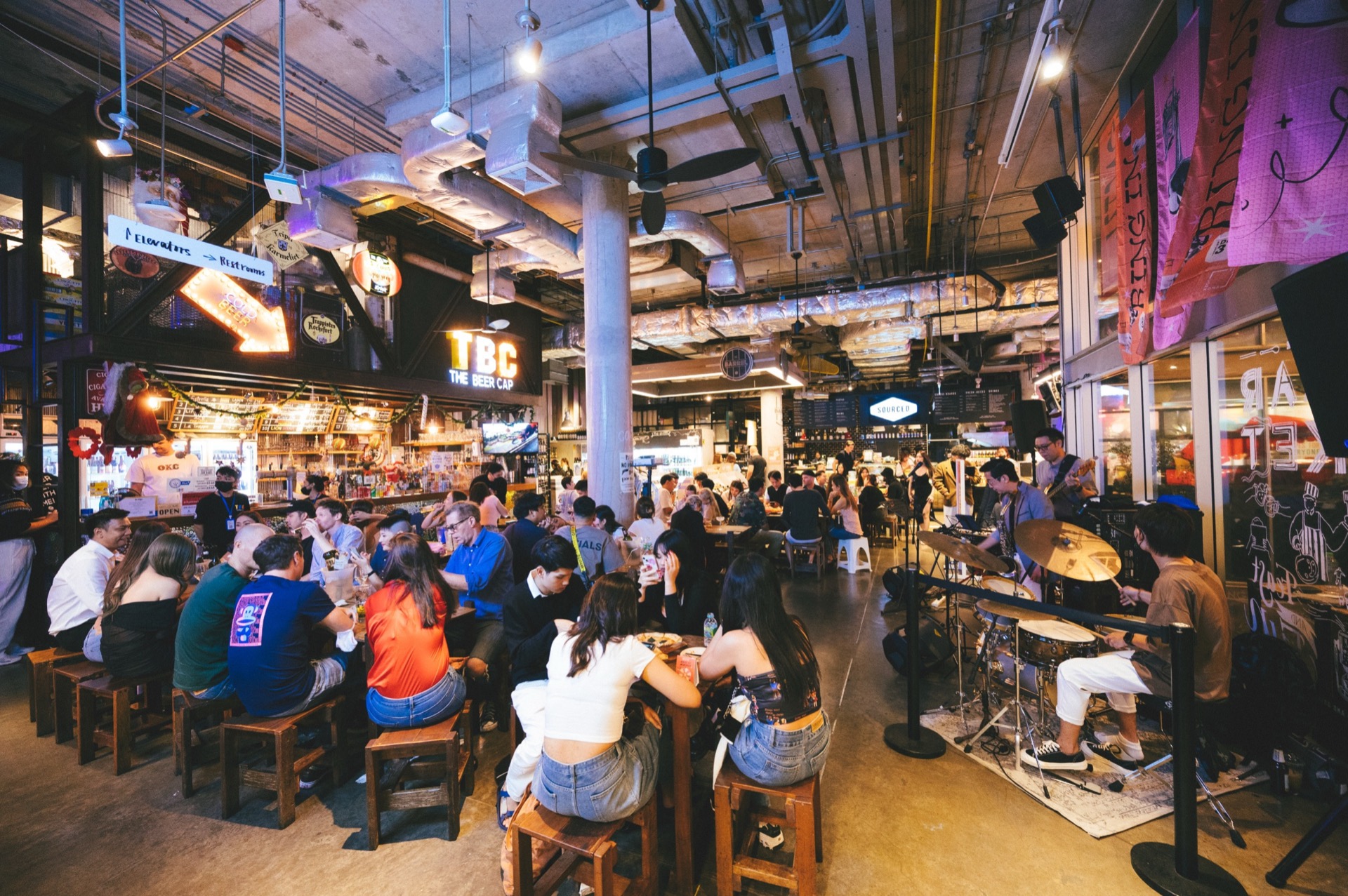 A band playing live at The Beer Cap, with the bar and the TBC sign behind
