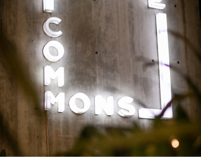 The illuminated theCOMMONS sign on a concrete wall